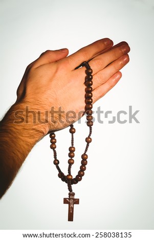 Hand holding wooden rosary beads on white background