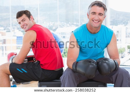 Men with box gloves smiling at camera in fitness studio