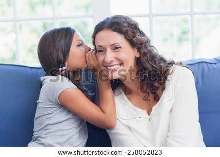 Mother and daughter whispering in the living room