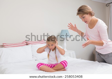 Mother scolding her naughty daughter at home in the bedroom