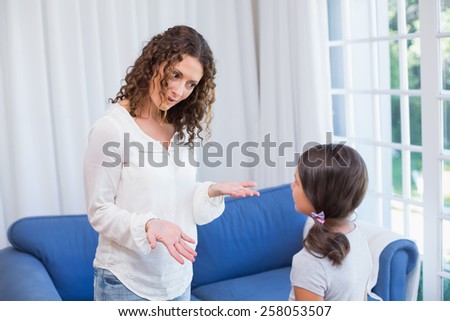 Upset mother looking at her daughter in the living room