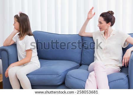 Mother scolding her naughty daughter at home in the living room