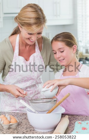 Mother and daughter making cake together at home in the kitchen