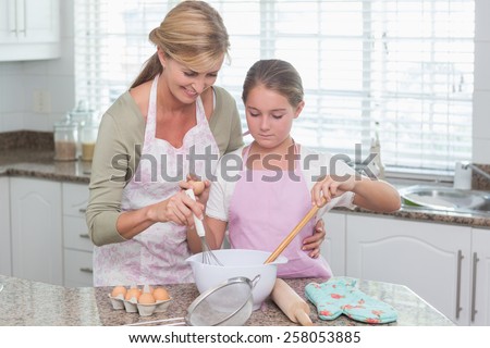 Mother and daughter making cake together at home in the kitchen