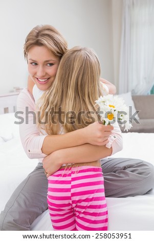 Mother and daughter hugging with flowers at home in the bedroom
