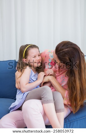 Mother and daughter laughing on couch at home in the living room