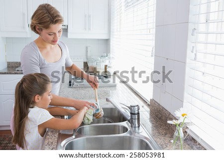 Mother and daughter washing up at home in kitchen