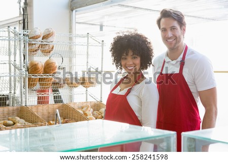 Portrait of happy co-workers standing behind the counter at the bakery