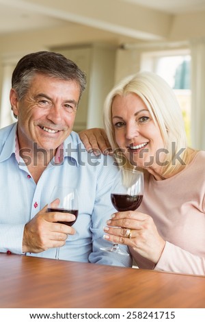 Happy mature couple drinking red wine at home in the kitchen