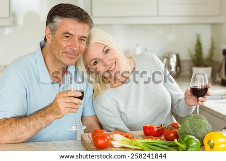 Happy mature couple having red wine while making dinner at home in the kitchen