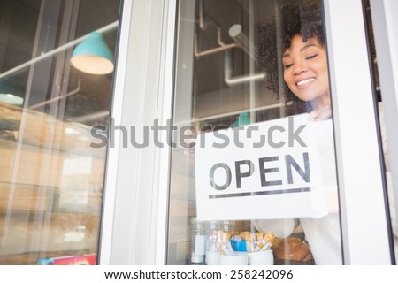 Pretty worker presenting open sign at the bakery