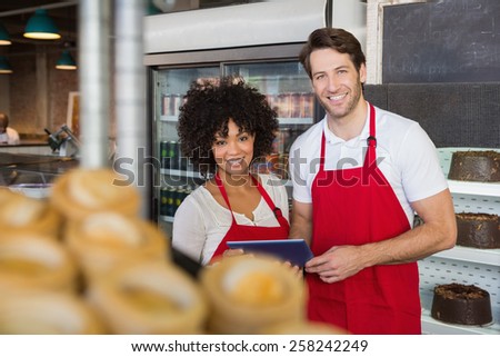 Smiling colleagues holding tablet pc at the bakery
