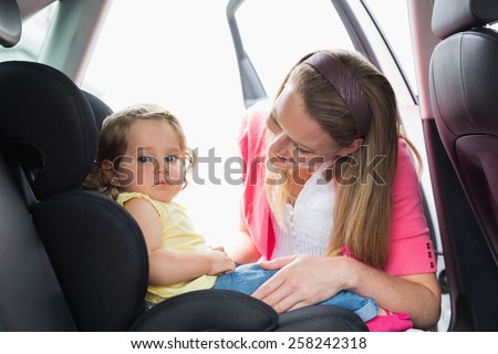 Mother securing her baby in the car seat in her car