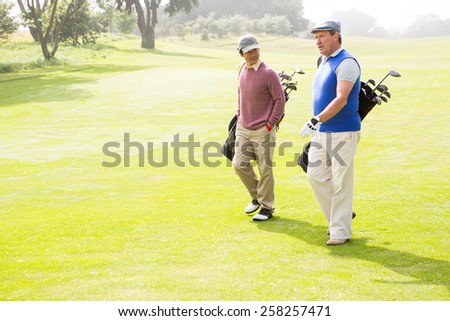 Golfer friends walking and chatting on a sunny day at the golf course