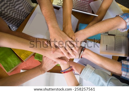 Close up of college students placing hands together over library table