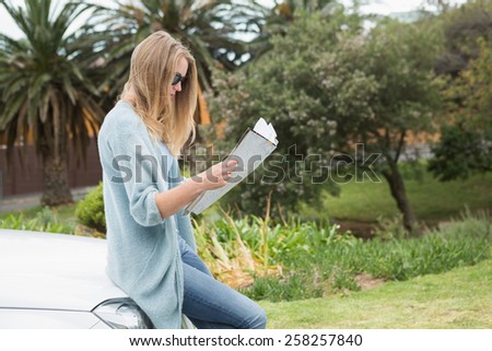 Young woman reading a map beside her car