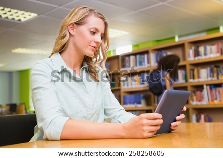 Pretty student studying in the library with tablet at the university