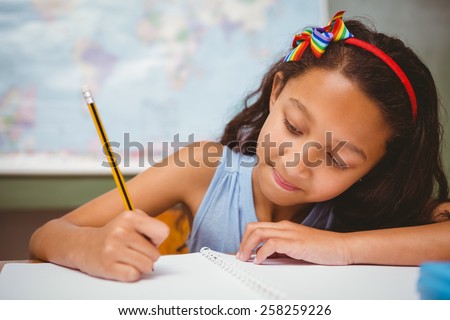 Portrait of cute little girl writing book in classroom