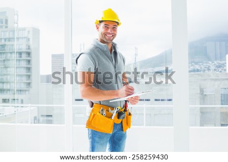 Portrait of smiling manual worker writing on clipboard in building
