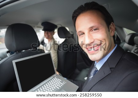 Businesswoman being chauffeured while working in the car