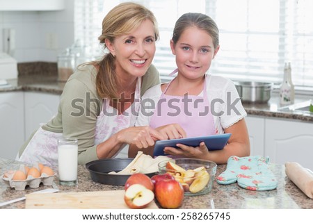 Happy mother and daughter preparing cake together at home in the kitchen