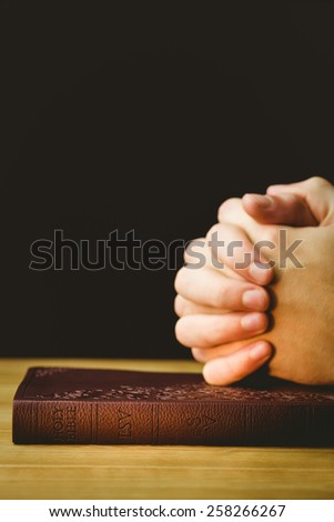 Man praying with his bible on wooden table