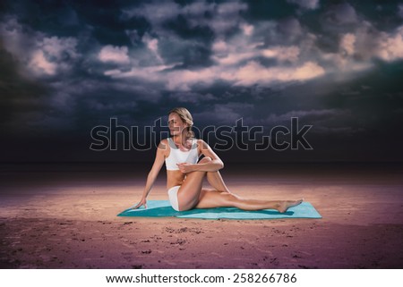 Gorgeous fit blonde in seated yoga pose against dark cloudy sky