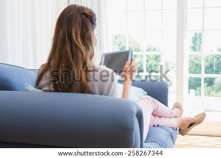 Casual woman using tablet on couch at home in the living room