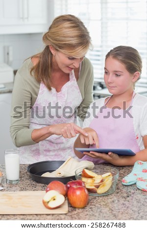 Happy mother and daughter preparing cake together at home in the kitchen