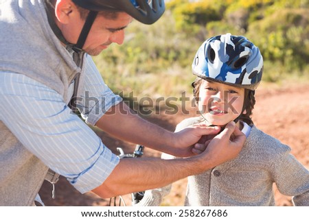 Father clipping on sons helmet on a sunny day