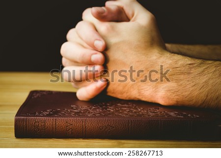 Man praying over his bible on wooden table
