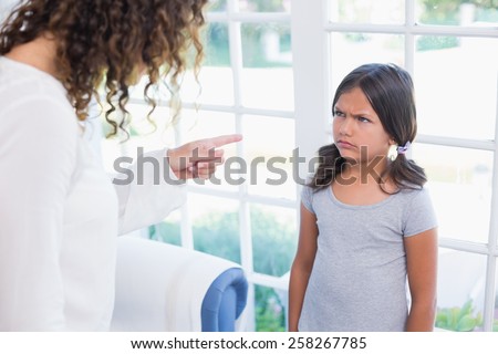 Angry little girl looking at her mother in the living room