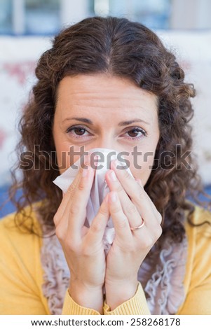 Sick woman blowing her nose in the living room