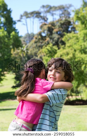 Little siblings hugging each other on a sunny day