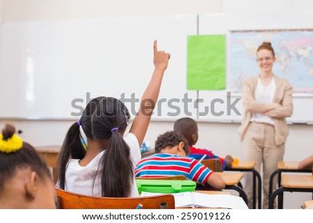 Pupils raising hand during geography lesson in classroom at the elementary school
