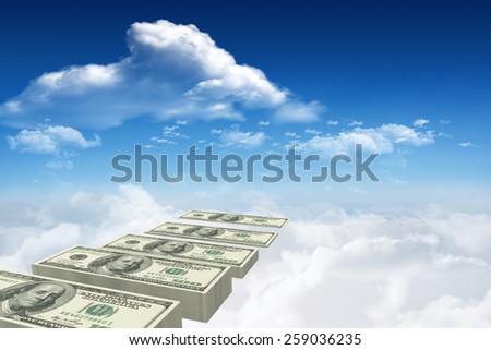 Stacks of dollars against bright blue sky with clouds