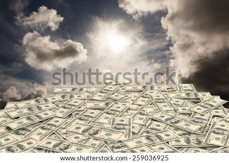Pile of dollars against dark sky with white clouds