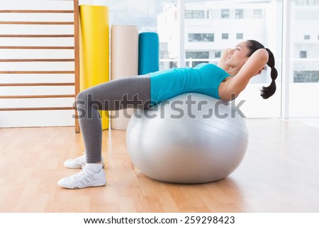 Woman exercising on fitness ball in fitness studio