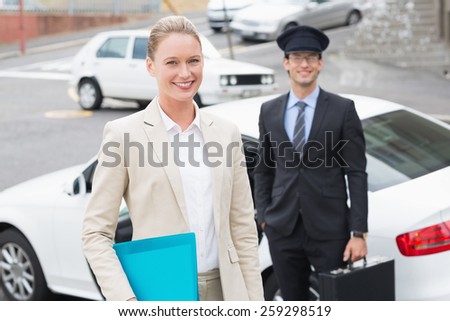 Businesswoman and her chauffeur smiling at camera outside the car