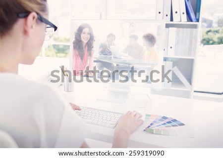 Composite image of smiling designer using tablet in office