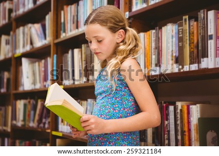 Cute little girl reading book in the library