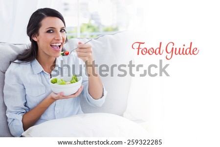 The word food guide against cheerful woman relaxing on the sofa eating salad