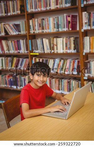 Portrait of little boy using laptop in the library
