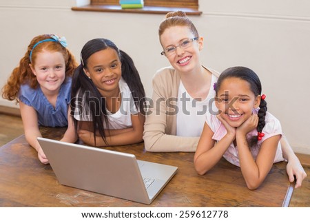 Teacher and pupils looking at laptop at the elementary school