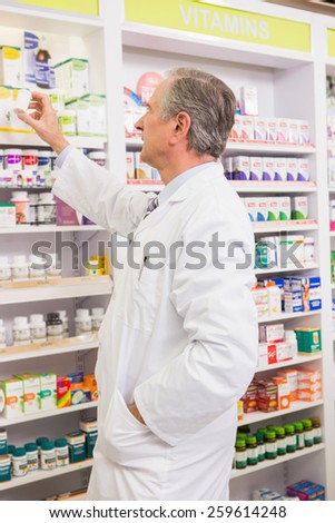 Pharmacist taking medicine from shelf in the pharmacy