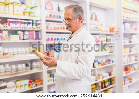 Smiling senior pharmacist reading prescription in the pharmacy
