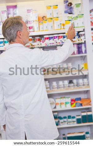 Senior pharmacist taking box from shelf in the pharmacy