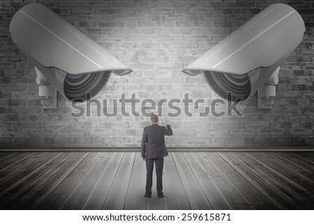 Businessman in suit pointing finger against grey room