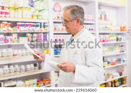 Senior pharmacist looking at medicine and prescription in the pharmacy