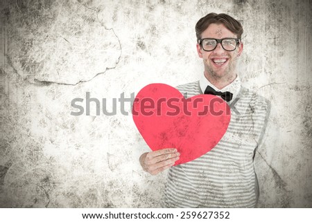 Geeky hipster holding heart card against grey background